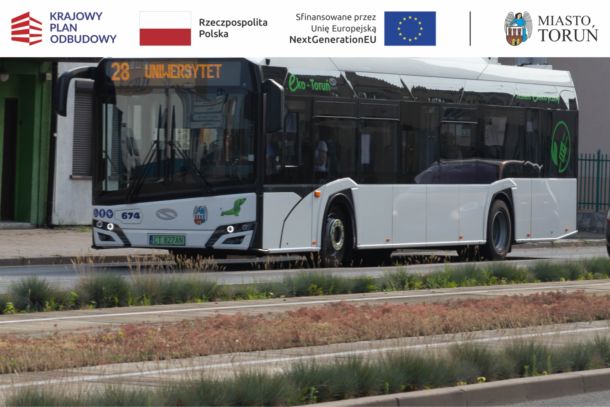 miejski autobus elektryczny koloru białego jadacy po jezdni wzdłuż torowiska tramwajowego