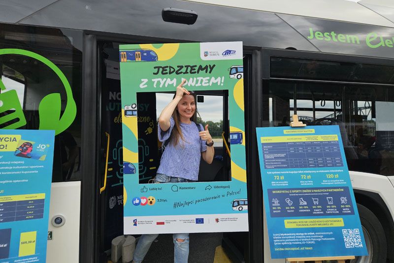 Uśmiechnięta kobieta w drzwiach elektrycznego autobusu